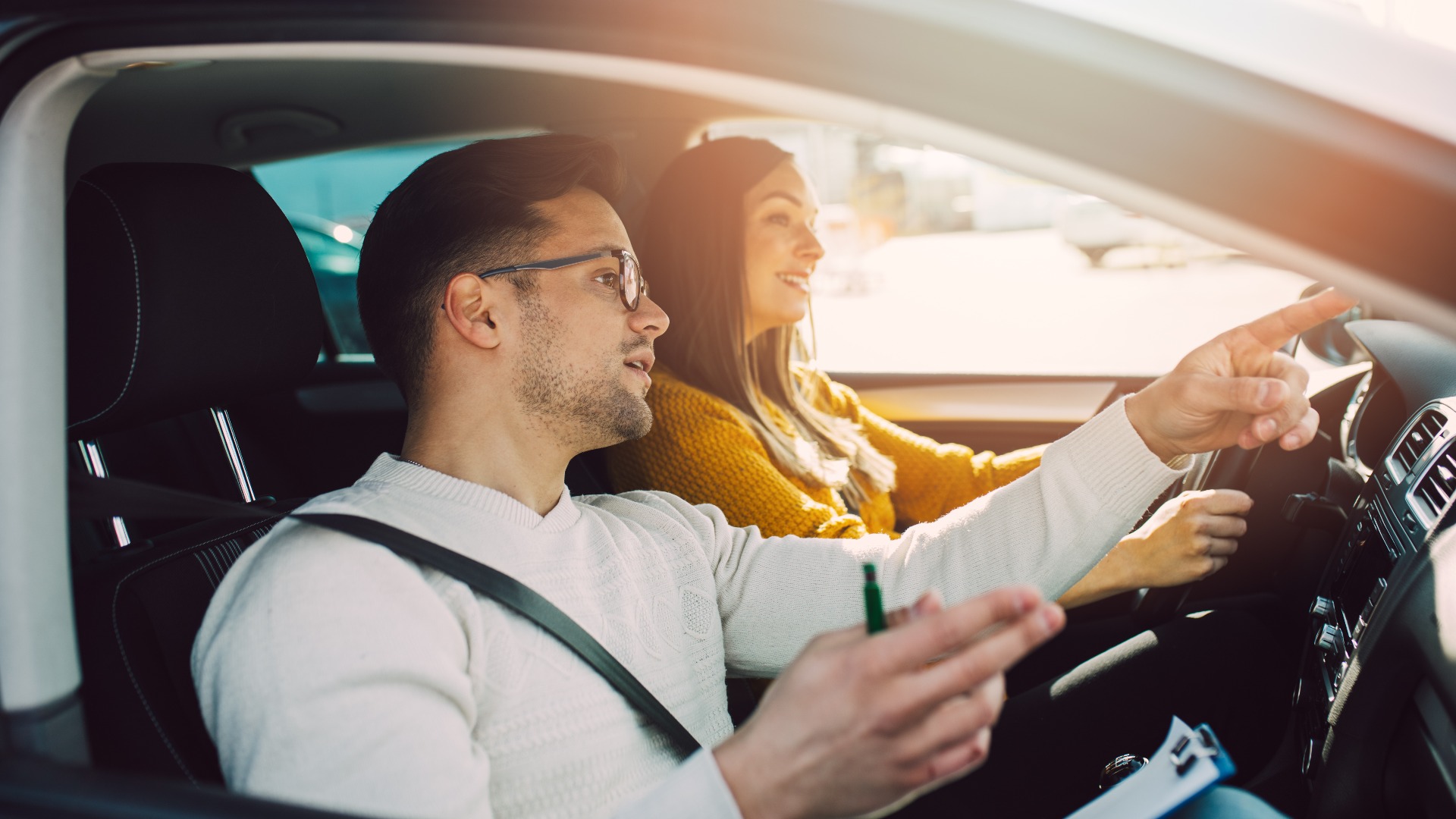 Fahrschule oder Fahrprüfung. Eine hübsche junge schwangere Frau lernt zusammen mit ihrem Fahrlehrer das Autofahren.